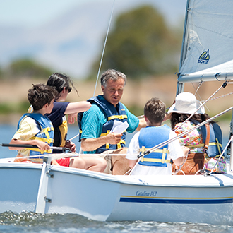 A group of kids in a boat wit an adult reading instructions