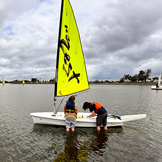 Two teens in the water with their boat.