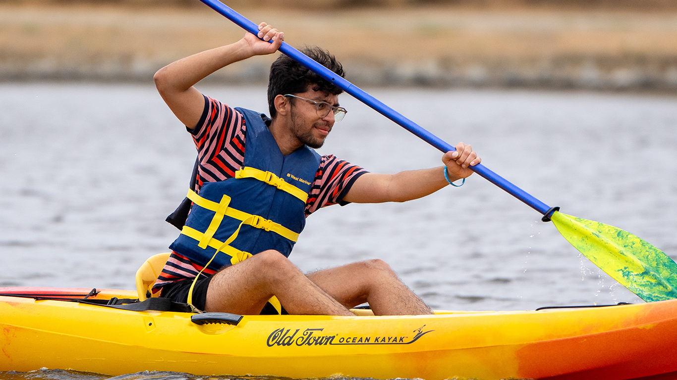 A young man kayaking on shoreline lake