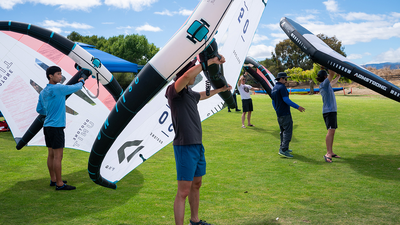 A group of young men ebing instructed on how to wingfoil.