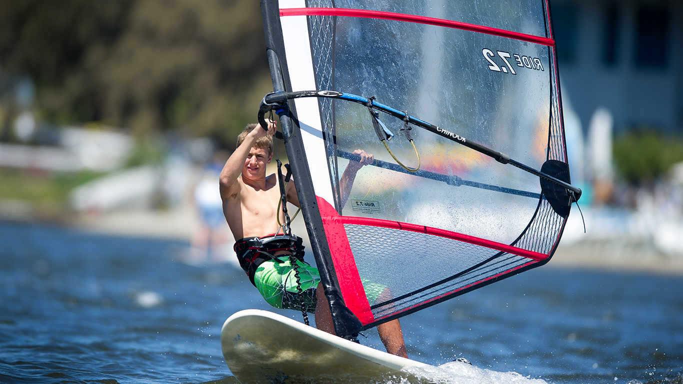 A boy windsurfing at shoreline.