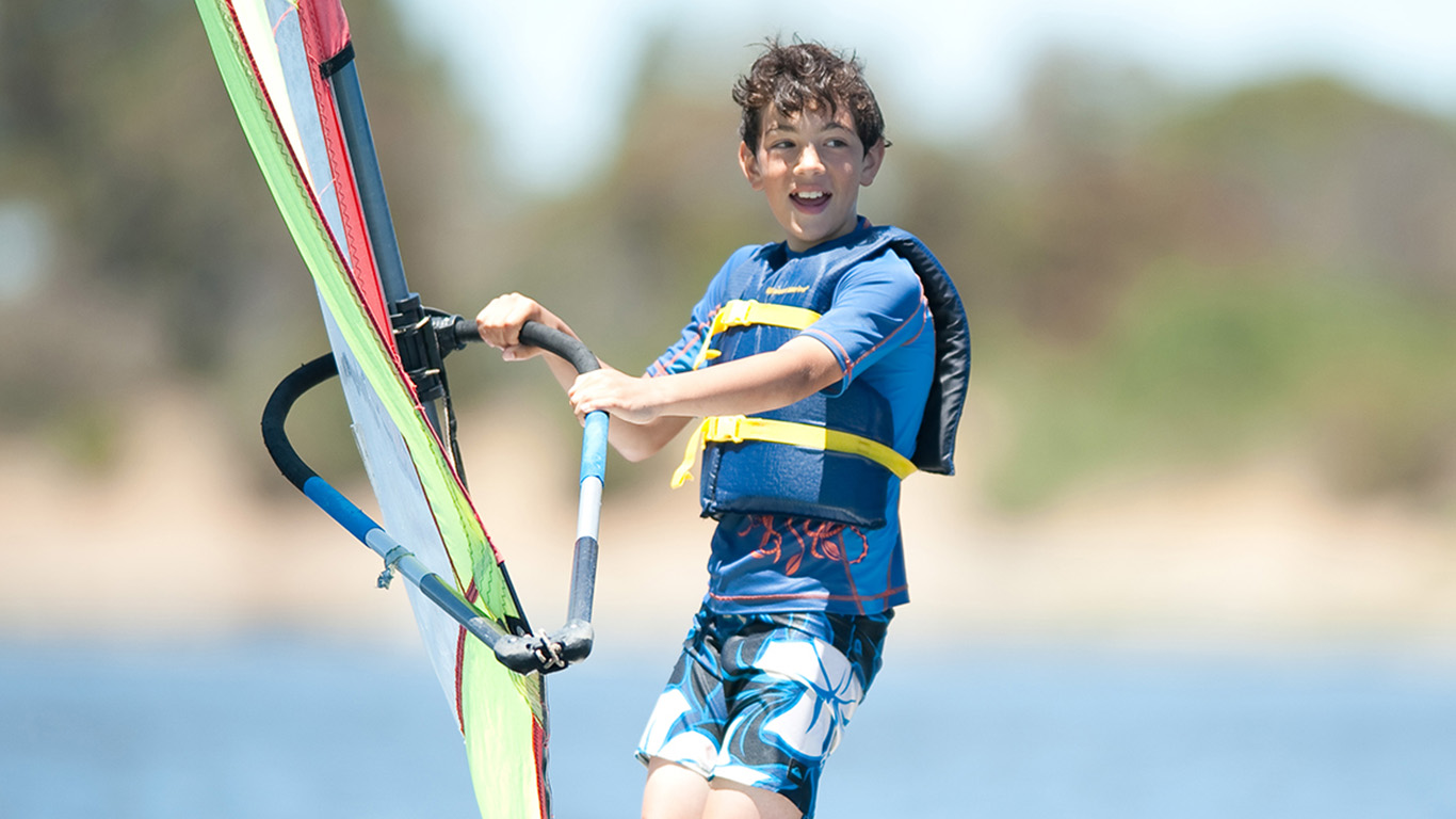 A boy on a windsurfing board on the lake