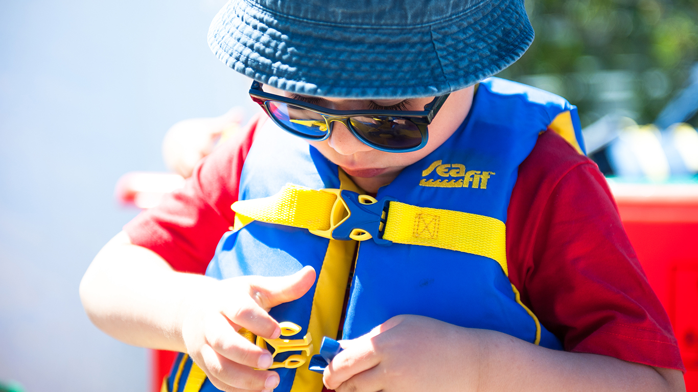 A kid putting on a personal floating device.
