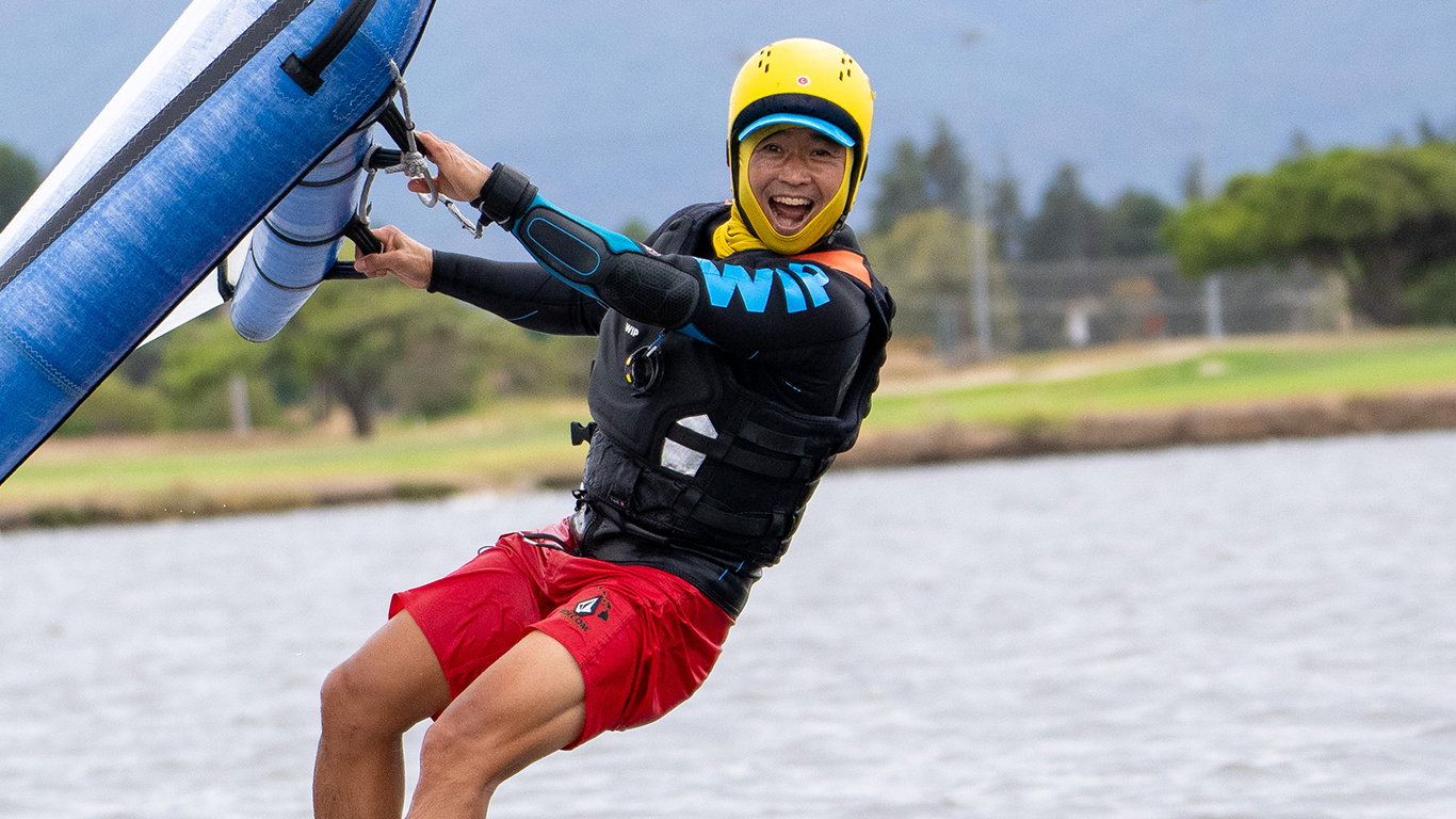 A young man on a wingboard having fun on shoreline lake
