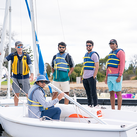 A group of men on the dock having a sailing lesson.