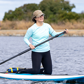 A lady getting ready to stand up on her paddle board