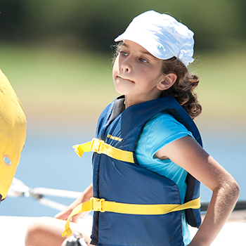 A girl with a hat on in a sailboat