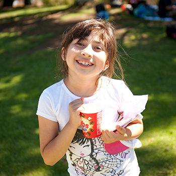 A young girl smiling while eating some chocolate.