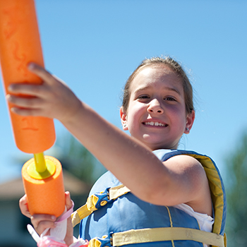 A young girl playing with a water gun.