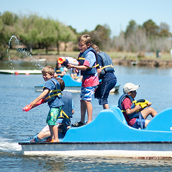 A group of boys playing with water guns in on a paddle boat