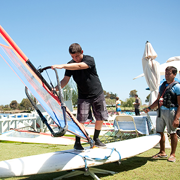 A sailing instructor teaching an adult student while their boats are docked.
