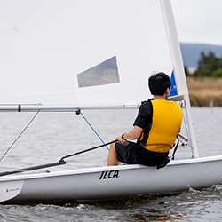 A young man controlling his sail boat.
