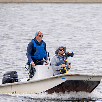 A photographer in boat at shoreline lake