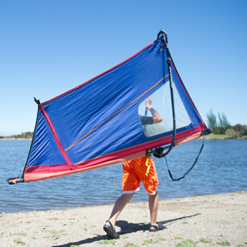  A young boy in a sail boat pulling on some of the ropes as he sails at shoreline Lake.